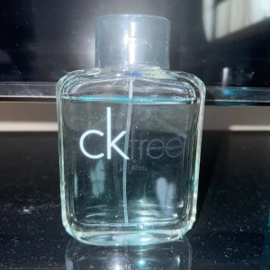 CK Free for Men Eau de Toilette - Säljer en fräsch och modern CK Free for Men Eau de Toilette från Calvin Klein. Flaskan är genomskinlig med en stilren design och blåaktig vätska. Perfekt för den som söker en lätt och uppfriskande doft.