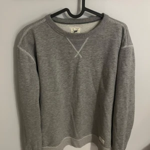 Grå sweatshirt från Lee - Säljer en stilren grå sweatshirt från Lee. Tröjan har långa ärmar och en klassisk rund halsringning med dekorativ söm framtill. Herr modell men passar tjejer super också. Aldrig använder. Nypris 600 kr. Pris kan diskuteras!❤️