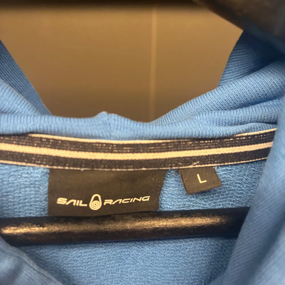 Säljer en snygg blå hoodie från Sail Racing. Den har en klassisk design med en liten logotyp på bröstet och en bekväm huva med dragsko. Perfekt för en avslappnad stil.. Neuletakit & Villapaidat.
