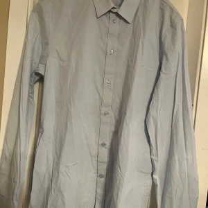 Ljusblå skjorta från Filippa K - Snygg ljusblå skjorta från Filippa K i storlek L. Skjortan har långa ärmar och knappar framtill samt vid ärmsluten. Perfekt för en stilren look.