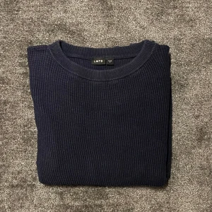 Mörkblå tröja från LMTD - Säljer en stilren mörkblå tröja från LMTD. Tröjan har en enkel design med rund hals och är perfekt för en avslappnad look. Den är tillverkad i ett bekvämt material som passar bra till det mesta i garderoben. Storlek S.