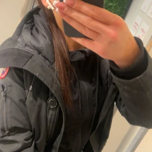 Svart parkajacka från Canada Goose - Snygg svart parkajacka från Canada Goose .Jackan har dragkedja och knappar framtill samt flera praktiska fickor. Den kommer utan päls. Köpt för 4000. Säljer för 950