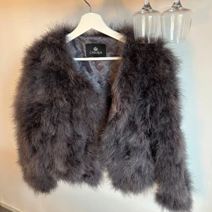 Grå pälsjacka från Chelsea - Säljer en lyxig och fluffig grå pälsjacka från Chelsea. Jackan har en elegant design med långärmade ärmar och är perfekt för att hålla dig varm och stilren under kyliga dagar.