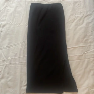 Svart långkjol med slits - En snygg svart rippad tajt kjol i storlek XS med en fin slits vid benet på höger sida. Kjolen är helt oanvänd och är i bra skick💗💗