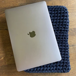 Mörkblå stickad datorväska - Säljer en superfin mörkblå datorväska som jag virkat själv. Passar perfekt för att skydda din laptop. Väskan är handgjord med ett tjockt och mjukt material som ger bra skydd mot stötar och repor. Passar min MacBook som är ca 33x22cm