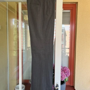 Grå kostymbyxor från Banana Republic - Säljer ett par snygga grå kostymbyxor från Banana Republic. Byxorna är tillverkade av 95% ull och 5% lycra, vilket gör dem både bekväma och stretchiga. De har en klassisk passform med raka ben och diskreta ränder. Perfekta för både kontoret och mer formella tillfällen. Byxorna har två bakfickor, fickor fram och hällor för bälte. US stl 0 vilket motsvarar XXS. Nypris ca $100. 