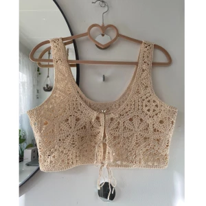 Virkad topp vit - Säljer denna superfina virkade toppen från H&M. Stl: XS, men sitter löst. Passar bättre på S-M om man vill ha den mer figurnära. Den är krämvit med knytdetalj på framsidan. Skriv om du har frågor✨