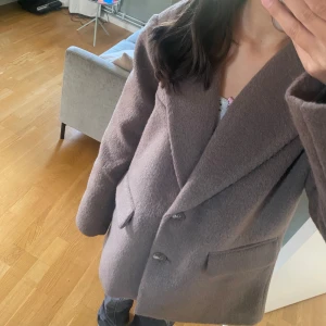 Brun kappa från Gina Tricot - Säljer en snygg brun kappa från Gina Tricot i storlek XS. Den är gjord av ett mjukt och varmt material, perfekt för höst och vinter. Kappan har en klassisk design med två knappar framtill och två fickor. Den är långärmad och har en normal passform. Perfekt för att hålla sig varm och stilren under de kallare månaderna.