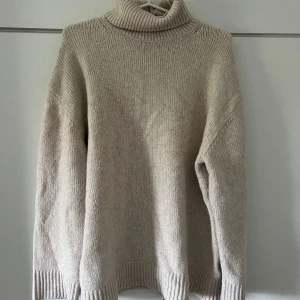 Beige stickad polotröja - Säljer en supermysig beige stickad polotröja. Den är perfekt för kalla dagar med sin höga krage och långa ärmar. Tröjan är i bra skick och har en normal passform. Perfekt för höst och vinter! 🍂❄️