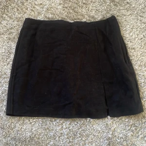 Svart mockakjol - Säljer en snygg svart linnekjol. Den är kort och har en enkel men stilren design. Perfekt för både vardag och fest! använd 1 gång💗