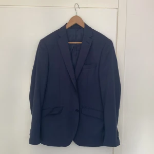 Kostym  - Kavaj och tillhörande kavajbyxor av märket Riley. Marinblå. Hittar ingen storlek men passar någon som vanligtvis har S/M. Byxorna skulle jag gissa är cirka 30 i både midja och i längd. 