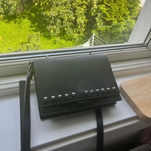 Väska med nitar - Väska från Steve Madden med nitar. En nit har tyvärr ramlat av, därav priset. Går säkert att sätta dit en ny. Inköpt för 900