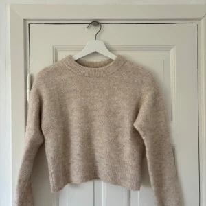 Stickad tröja - Mysig beige stickad tröja från Lindex i storlek XS. Perfekt för kyliga dagar med sin croppade design och långa ärmar. Tröjan har en enkel och stilren look som passar till det mesta. Ett måste i garderoben för höst och vinter! 🍂