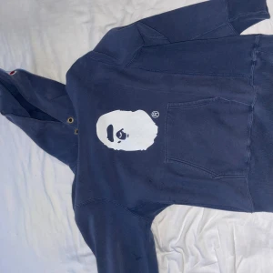 Blå hoodie med tryck - Säljer en blå hoodie med ett coolt tryck på framsidan. Den har en stor ficka fram och är perfekt för en avslappnad stil. Passar bra till både höst och vår. Skön och bekväm att ha på sig!