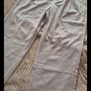 Beige byxor från 157 - Säljer ett par stilrena beige byxor från 157 i storlek L. Byxorna har en klassisk design med hög midja och raka ben. Perfekta för både vardag och fest. Några små tecken på användning men i bra skick.