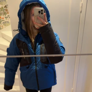 Blå vinterjacka från Sail Racing - Säljer en blå vinterjacka från Sail Racing i storlek M. Den har Gore-Tex-material och många praktiska fickor. Jackan har en pufferstil med lång ärm och dragkedja. Perfekt för kalla vinterdagar med sin varma och skyddande design. Original pris: (4500kr). Den är i väldigt väldigt bra skick knappt använd. 
