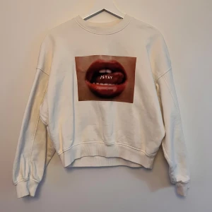 Vit sweatshirt från Stay - Säljer en vit sweatshirt från Stay i storlek XS. Den har ett coolt tryck med ett par läppar och texten 'STAY' på framsidan. Tröjan är långärmad och perfekt för en avslappnad stil. Superbekväm och lätt att matcha med jeans eller leggings!❣️