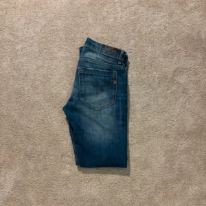 Dondup med slitningar  - Säljer ett par snygga blå jeans med coola slitningar på framsidan. De har en tight passform och är perfekta för en avslappnad stil. Jeansen är i väldigt bra skick D märker sitter i gott skick👍 Bara höra av dig vid funderingar 