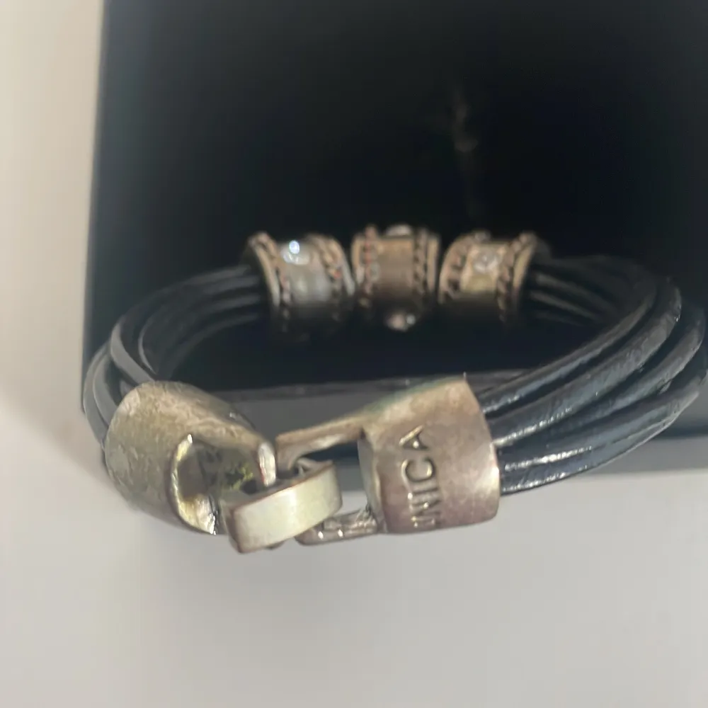 Snyggt svart armband med flera remmar och coola silverdetaljer. Armbandet har tre silverringar med glittriga stenar som ger en extra touch. Perfekt för att piffa upp vilken outfit som helst! Lås i silverfärg för säker passform.. Accessoarer.