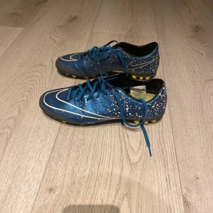 Nike Mercurial Victory  - Säljer ett par gamla coola blå fotbollsskor från Nike med vita stänkdetaljer. Skorna är i bra skick