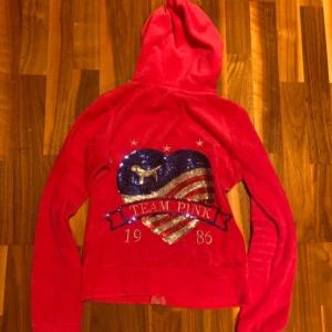 Röd hoodie från PINK - Säljer en superfin rosa hoodie från Victoria’s secret PINK i storlek S. Den har en cool paljett-design på ryggen med texten 'TEAM PINK 1986'. Mjuk och bekväm med dragkedja och fickor fram. Jag tar emot trades men annars är det fast pris 🥰
