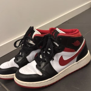 Nike Air Jordans i svart, vitt och rött - Säljer ett par klassiska Nike Air Jordans i svart, vitt och rött. Skorna har en snygg design med snörning och den ikoniska swoosh-loggan i rött. Perfekta för både vardag och sportiga tillfällen. Använda fåtal gånger men är ändå i bra skick. Priset kan även diskuteras. Hör gärna av er om ni funderar över något!