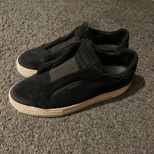 Arigato 360 Laceless - Säljer ett par stilrena svarta sneakers från Arigato i mocka. De har en enkel och modern design utan snörning, vilket gör dem lätta att ta på och av.  Säljes för 599, nypris 2600kr.