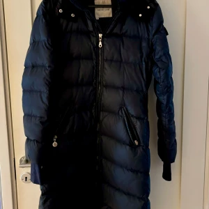 Mörkt blå dunkappa från Moncler - Säljer en snygg och varm dunkappa från Moncler. Jackan har en dragkedja framtill och praktiska fickor med dragkedjor. Perfekt för kalla vinterdagar. Den är i mycket bra skick och redo för nya äventyr! 🖤
