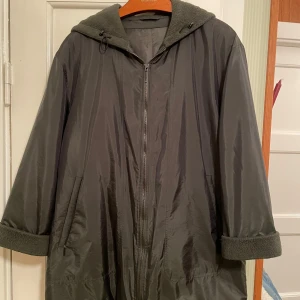 Jacka Steilmann - Mörkgrön, halvblank, lätt och elegant jacka/kappa med fleecefoder i huvan och i änden av ärmarna. Använd men välvårdad. Dragkedjor i fickorna, innerficka med kardborrband.