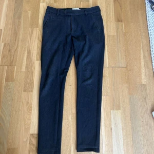 Mörkgrå kostymbyxor från Les Deux - Snygga mörkgrå kostymbyxor från Les Deux i storlek 28. Perfekta för både formella och semi-formella tillfällen. Byxorna har en klassisk design med knappar och bälteshällor. De är i mycket bra skick och redo att bäras till nästa event!