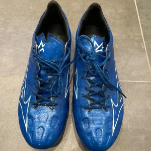 Mizuno alpha elite fg - Säljer ett par Mizuno alpha elite fg i mycket bra skick. Använda 2-3 ggr på konstgräs. Säljer pga att de inte passade. OBS! Storlek 43, Passar även 44 för er som gillar att ha riktig nära-bollkänsla. Priset är ej hugget i sten. Köptes för 2300 kr. Skriv för mer info