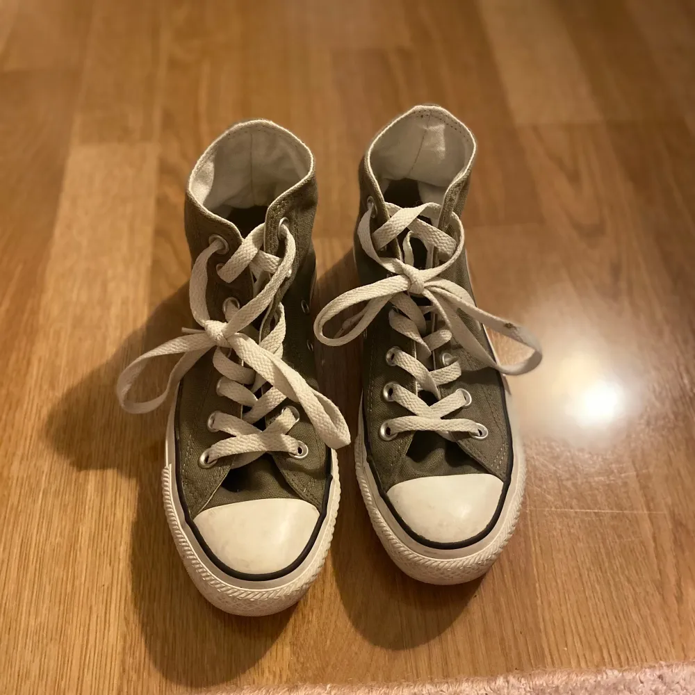 Säljer ett par klassiska gröna Converse All Star sneakers i bra skick. De har vita snören och en vit gummisula med den ikoniska loggan på sidan. Perfekta för en avslappnad stil och funkar året runt!. Kengät.