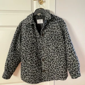 Grå leopardmönstrad jacka - Säljer en cool trendig leopardmönstrad jacka i bra skick. Den har en fin passform och är perfekt för höst och vår. Jackan har långa ärmar och knappar framtill. Perfekt för att ge din outfit något extra! Den är lite oversize i barnstorleken 11-12/152cm 🐆