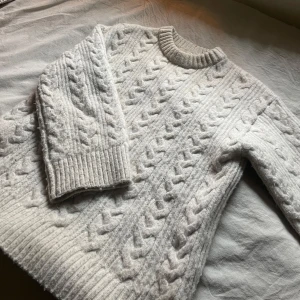 Beige stickad tröja  - Mysig beige stickad tröja från H&M i storlek XS. Perfekt för kyliga dagar med sitt flätmönster och ribbade muddar. Tröjan har en klassisk design som passar både till vardags och lite finare tillfällen. Superbekväm och stilren! 🍂Jättevarm och skön! Stor i storleken skulle jag säga