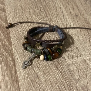 Bohemiskt armband med pärlor och läderdetaljer - Säljer ett coolt bohemiskt armband med en mix av pärlor i olika färger och läderdetaljer. Armbandet har en justerbar rem. 