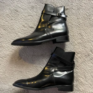 Svarta boots med spänne - Snygga svarta boots i skinn med ett elegant spänne på sidan. Köpta för 1495 nypris och aldrig använda eftersom de var för små! Perfekta för både vardag och fest, dessa boots har en stilren design med låg klack och spetsig tå. Skriv gärna till mig om du har några frågor!