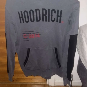 Grå hoodie från Hoodrich - Säljer en grå hoodie från Hoodrich med svart text och detaljer. Tröjan har en stor ficka framtill och en bekväm huva. Perfekt för en avslappnad stil. Nypris 1100, men säljs här för 600