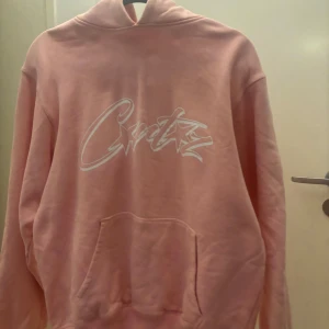 Corteiz - Säljer en snygg rosa hoodie från Corteiz med vit text på bröstet. Den ser skrynklig ut men jag kommer tvätta och stryka innan jag postar! Den är använd 1 gång och 10/10 skick. Den passar både xs och S