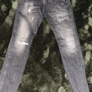Grå jeans med slitningar - Snygga grå jeans med slitningar på framsidan för en trendig look. De har en klassisk femficksdesign och en rak passform. Perfekta för en avslappnad stil.