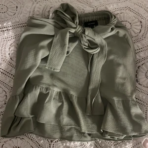 Grön kjol med volang och knyt ❤️❤️ - Säljer en söt grön kjol från veromoda med volangdetaljer och knyt framtill. Perfekt för en stilren look. Kjolen har en luftig passform och är tillverkad i ett lätt material. Fint skick, använd fåtal gånger ❤️❤️