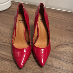 Röda pumps från H&M - Snygga röda pumps från H&M i storlek 37. De har en spetsig tå och en elegant klack som ger en stilren look. Perfekta för att sätta färg på din outfit.