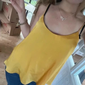 Gul linnetopp från Stradivarius - Snygg gul linnetopp från Stradivarius med tunna axelband. Perfekt för varma sommardagar. Toppen har en enkel och stilren design som gör den lätt att matcha med olika outfits.