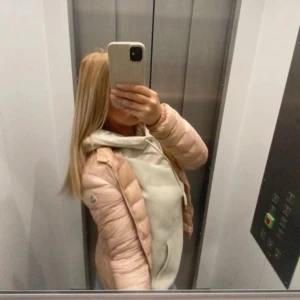 Beige dunjacka från Moncler - Säljer en snygg beige dunjacka från Moncler. Jackan har en klassisk pufferdesign med långa ärmar och en diskret logga på ärmen. Perfekt för kyligare dagar och ger en stilren look. Passar bra till både vardag och mer uppklädda tillfällen. Kom privat för mer bilder (angånde att den är äkta)