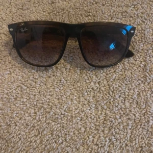 Svarta solglasögon från Ray-Ban - Snygga svarta solglasögon från Ray-Ban med klassisk design. De har en stilren svart båge och mörka glas som ger ett coolt intryck. Perfekta för soliga dagar!