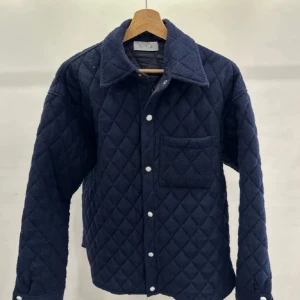 Mörkblå grisch jacka - Snygg mörkblå grisch jacka med långa ärmar och knappar framtill. Jackan har en klassisk krage och en praktisk bröstficka. Perfekt för kyligare dagar.