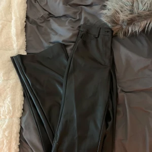Svarta skinnbyxor - Snygga svarta skinnbyxor med hög midja ben. Byxorna har fickor bak och bälteshällor, vilket ger en stilren look. Perfekta för en trendig outfit. Går att göra det low waist också!!