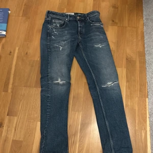 Blå jeans från Replay - Snygga blå jeans från Replay med slitna detaljer och en klassisk femficksdesign. De knappar som jylf och knapp framtill. Perfekta för en avslappnad stil. Nypris 2000 säljer för att dom är för små skick 9/10. Storlek W31, L32. Pris kan diskuteras 