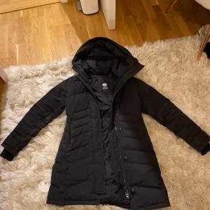 Säljer en svart dunjacka från Canada Goose med huva och dragkedja. Jackan är perfekt för kalla dagar. 