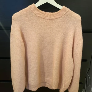 Rosa stickad tröja från H&M - Mysig rosa stickad tröja från H&M med rund halsringning och långa ärmar. Perfekt för kyliga dagar och ger en avslappnad look. Passar bra till jeans eller kjol.