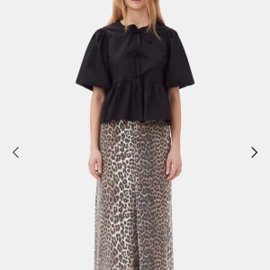 Svart blus med knytning - Snygg svart blus med puffiga kortärmar och knytning framtill. Den har en lös passform och volangdetaljer vid midjan. Perfekt för en stilren look.